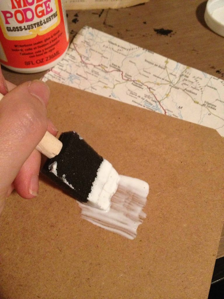 Using a craft box, spread mod podge on the cardboard background of the shadowbox - this will help attach the vintage map to the shadowbox background.