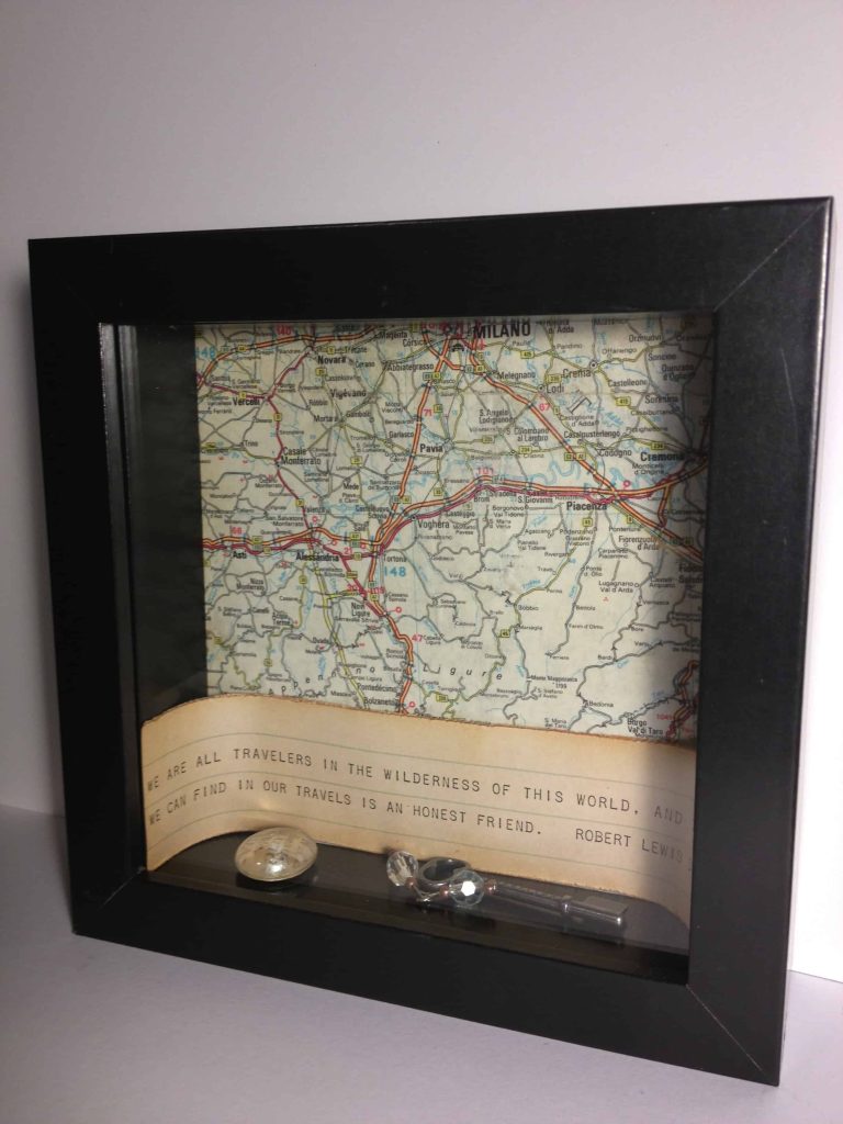 The completed vintage map shadowbox is perfect for anyone who loves traveling. This vintage shadowbox has a black frame and is filled with a vintage map and trinkets.