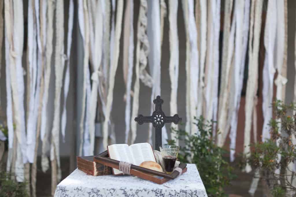 Making your own DIY wedding decor is a create cheap wedding hack! We made our ceremony backdrop using long ripped pieces of fabric tied to jute string.