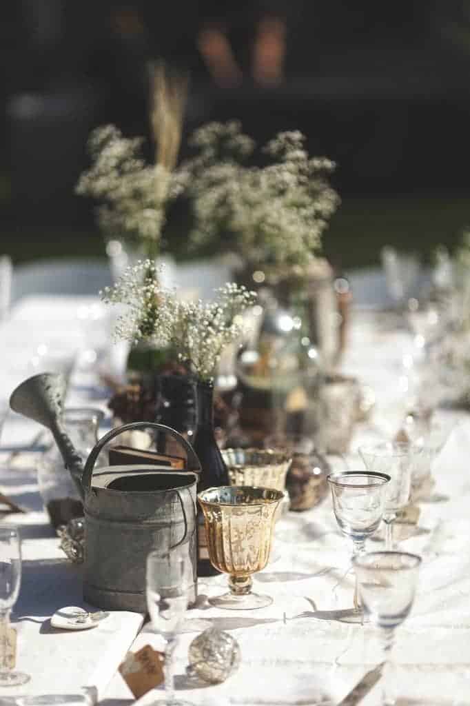 A close up look at some of the rustic centerpieces we put together for our cheap wedding decor. We used items like a metal watering can, small vases, and gold goblets