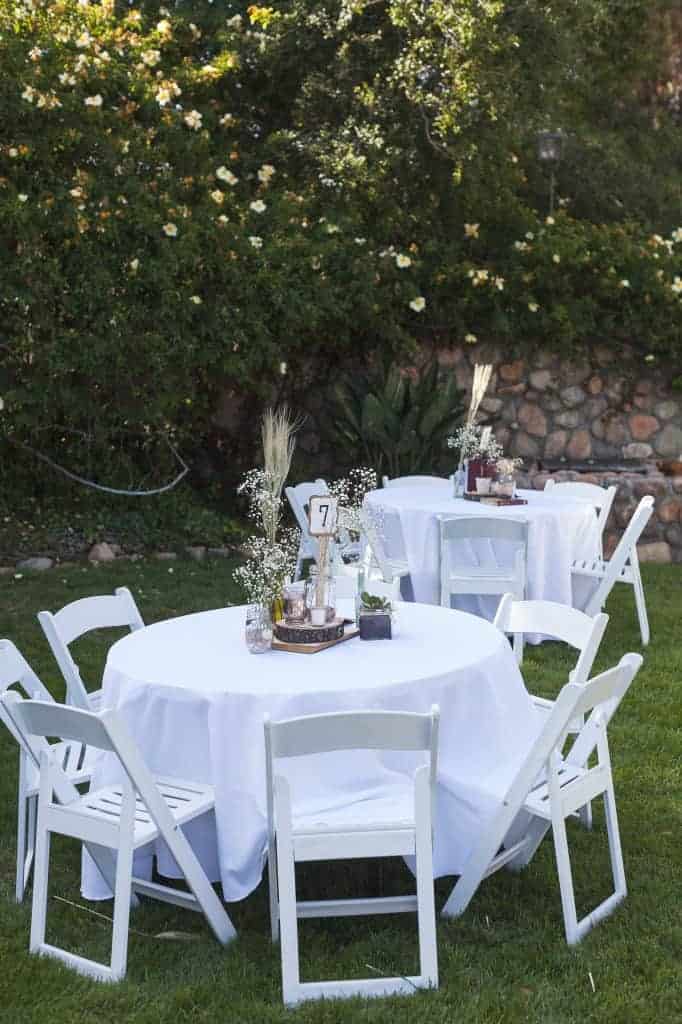 Looking for cheap wedding ideas? Make your own DIY centerpieces like these rustic wedding table centerpieces with flowers, log cutouts, and tea light candles.