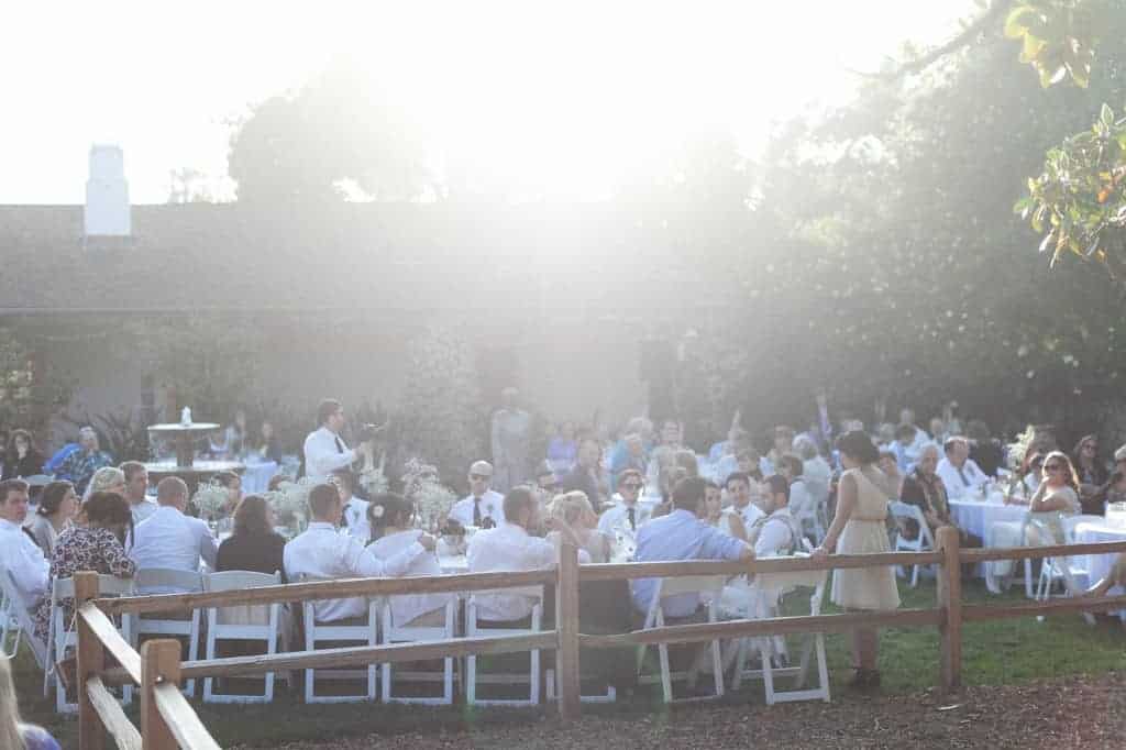 Our wedding guests sit at long dining tables during our outdoor wedding reception.