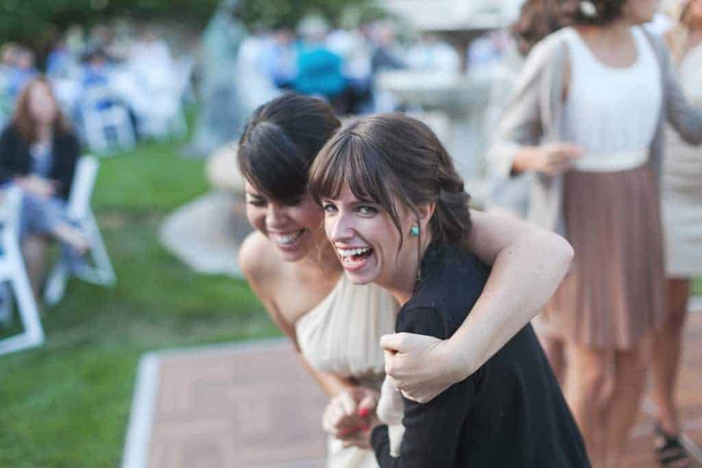 Two smiling wedding guests enjoying the reception on the dancefloor. If you're looking for cheap wedding ideas, having a friend or family member DJ your wedding will save money.