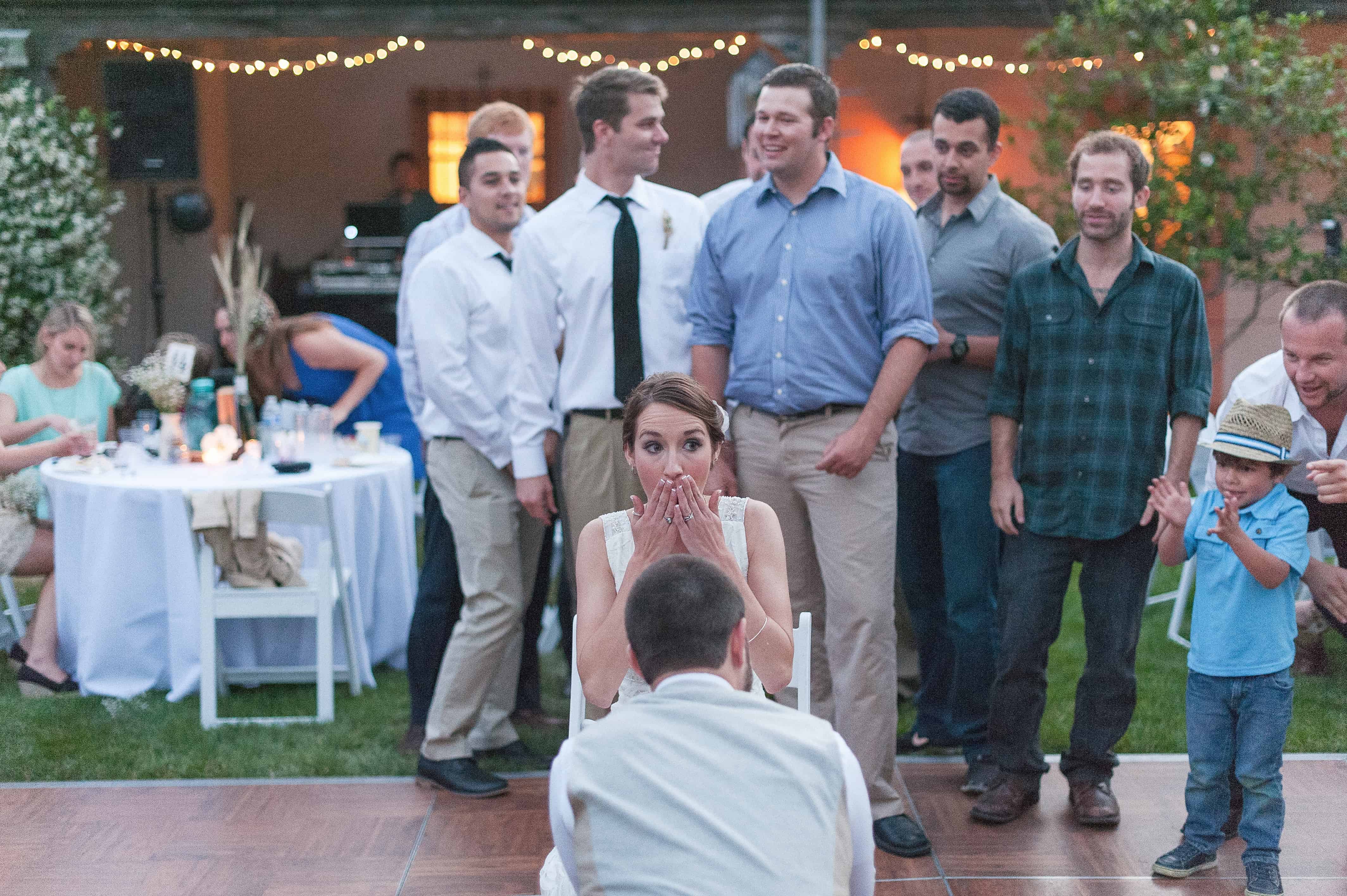 groom removing the garter to bride with guests happily watching