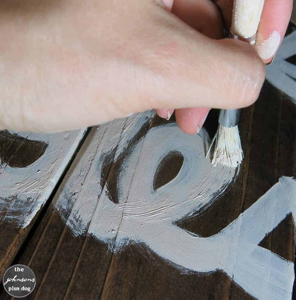 Using a taklon filbert brush to get a rough, rustic looking brush effect on this rustic painted wood sign.
