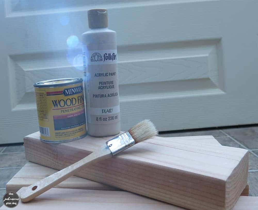 Supplies needed for painting a rustic wood sign. You will need wood, a wood stain in the color of your choice, acrylic paint for painting on the saying, and a paint brush.