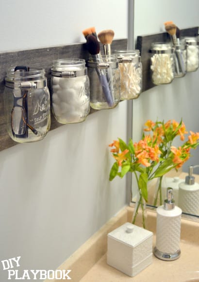 Reclaim your bathroom countertop space by adding a mason jar organizer to the wall to hold small things, like cotton balls and makeup brushes