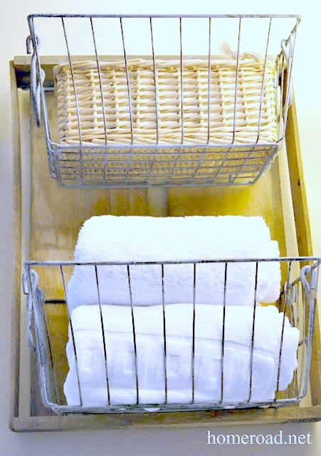 Make your own bathroom storage rack using wire baskets and wooden crate, which is perfect for storing towels and toilet paper rolls