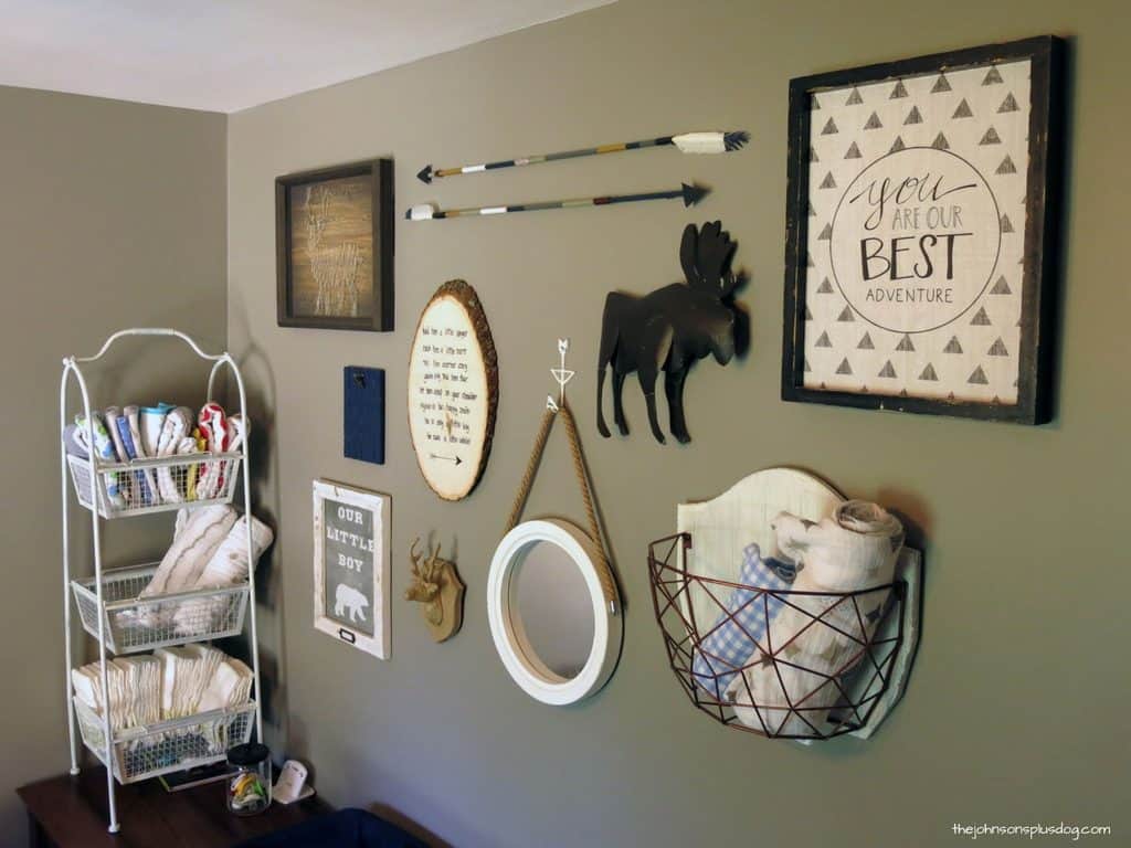 Woodland Nursery with diy arrows, frames, moose, circle wood with texts, hanging towel shelf and baby essential stand on the side of the room