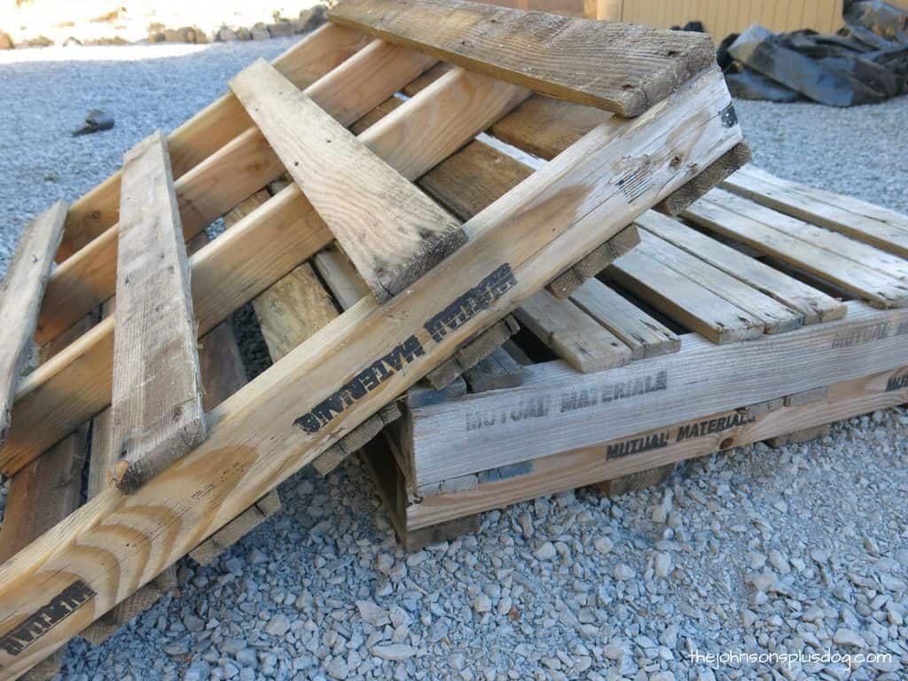 Two wooden pallets lay on the gravel ground. We'll use these to create a DIY pallet wood AC unit cover.