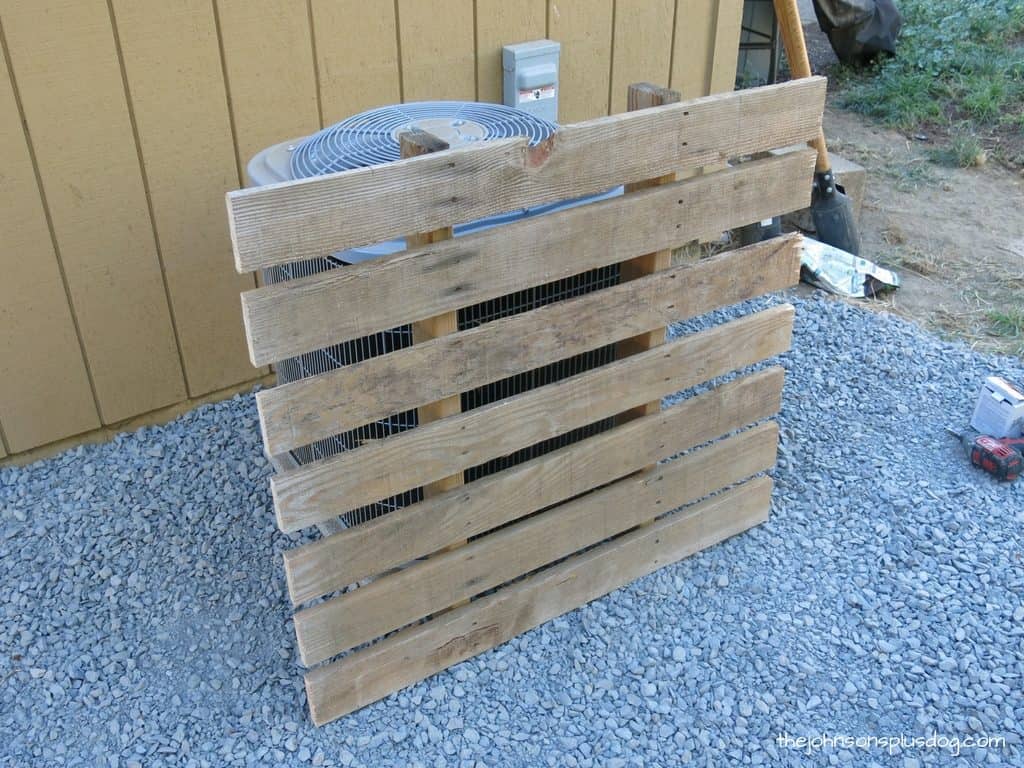 A portion of the broken-down wooden pallet sits leaned up against our AC unit.