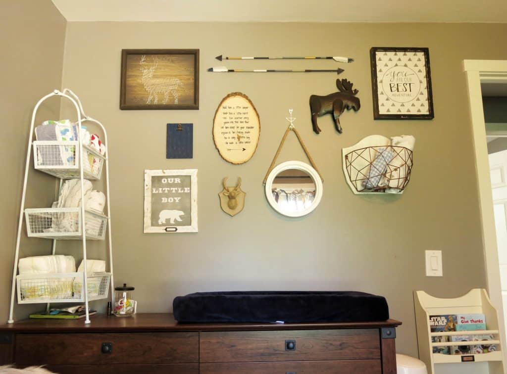full view of a single gallery wall in a rustic woodland themed nursery above a dresser changing table