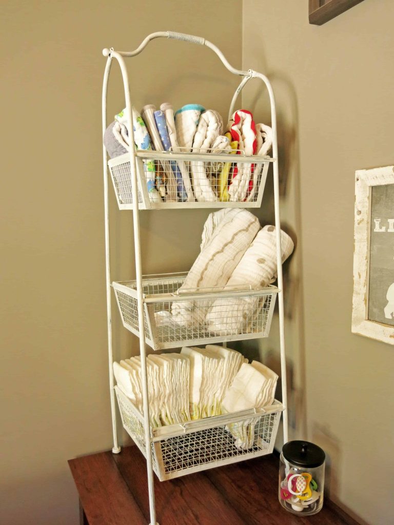 a 3 shelf storage area for a baby changing station with diapers, burp cloths and swaddle blankets