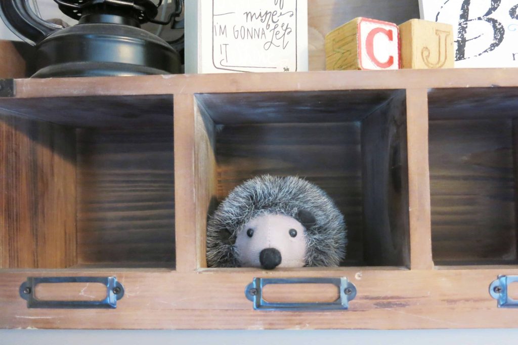 close up of a stuffed hedgehog toy on a wooden shelf in a woodland nursery