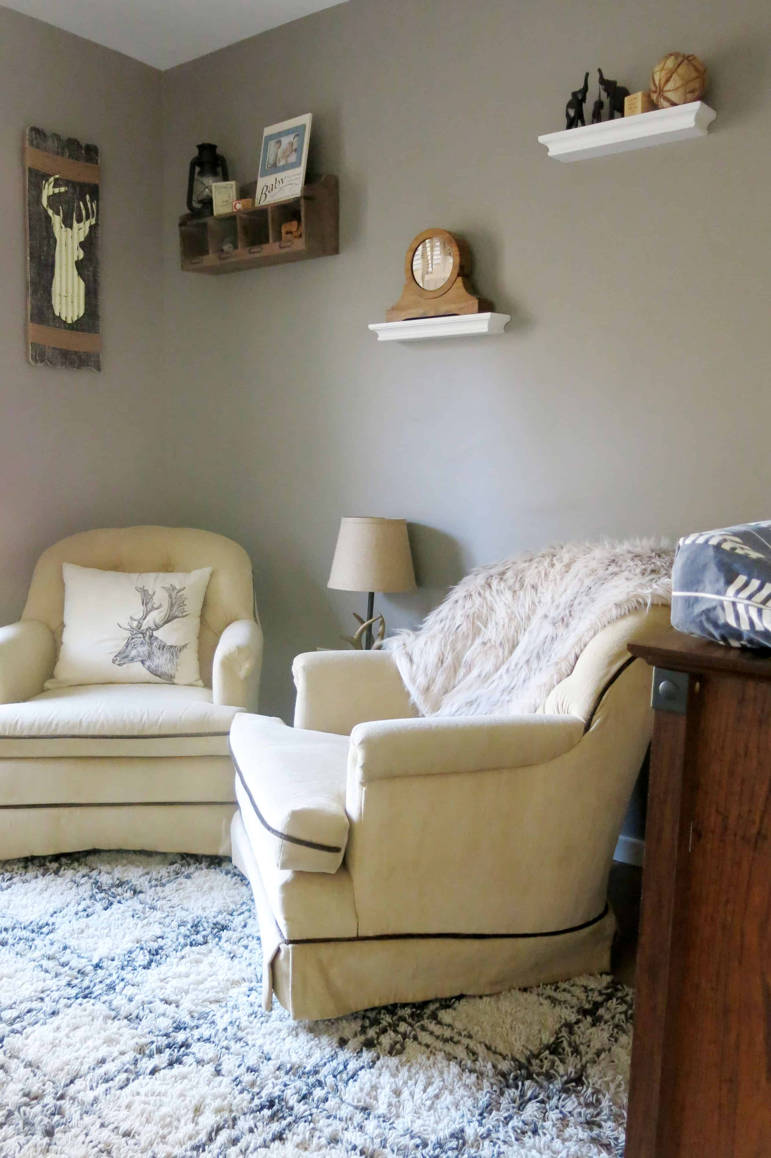 sitting area in a rustic woodland themed nursery with gray walls, tan sitting chairs, a plaid looking rug