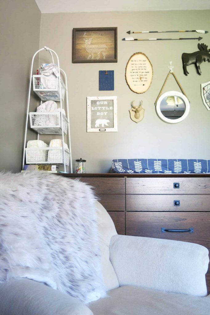 a nursery with a faux fur throw over a chair, a dresser used as changing table, and a gallery wall over the dresser