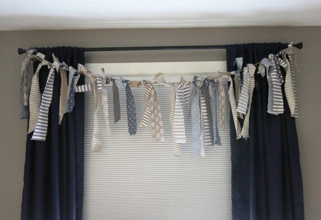 fabric strip banner hanging in front of a window with navy blue curtains and white cellular shades