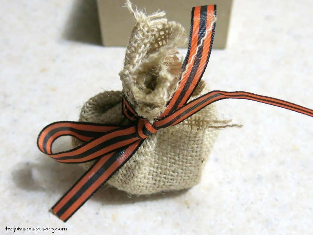 A small burlap sack tied with orange and brown ribbon