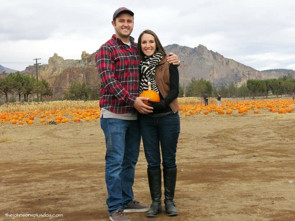 Chelsea and Logan posing for their Fall baby announcement picture at a pumpkin patch