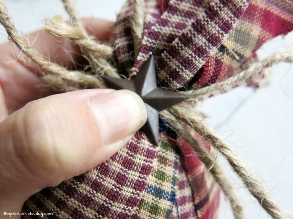 Attaching a rustic metal start accent to the top of a homemade fabric ornament. 