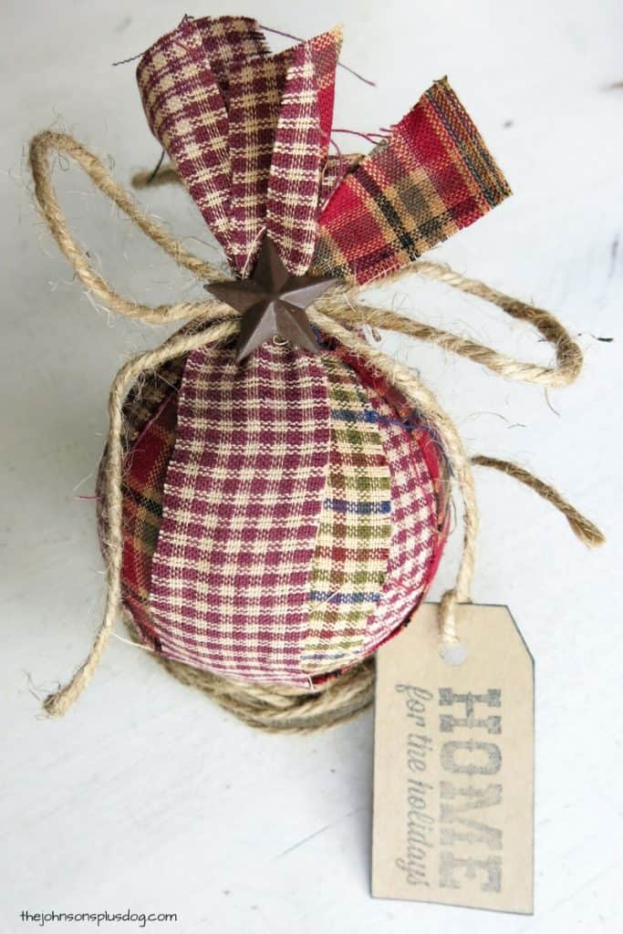 A full view of the first completed homemade fabric ornament, made with strips of plaid homespun fabric, twine, and rustic star accents.