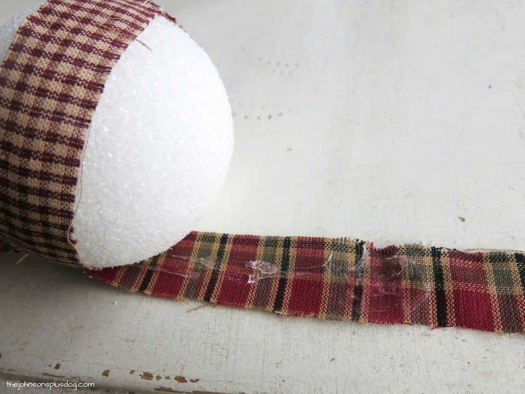 Applying craft glue to the homespun fabric stripes, which will help adhere the fabric to the craft ball.