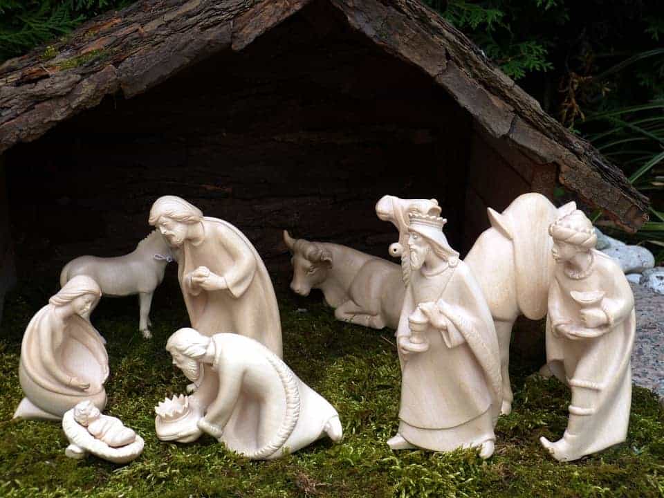 White stone figurine nativity scene on a bed of moss with bark stable