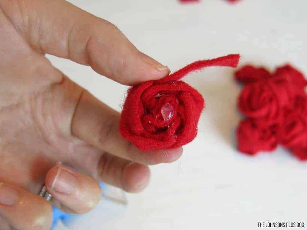 Woman hand holding a rosette made out of rolled red felt strip