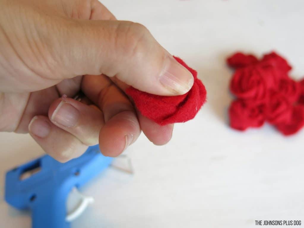 Woman hand pressing a rosette made out of rolled red felt strip