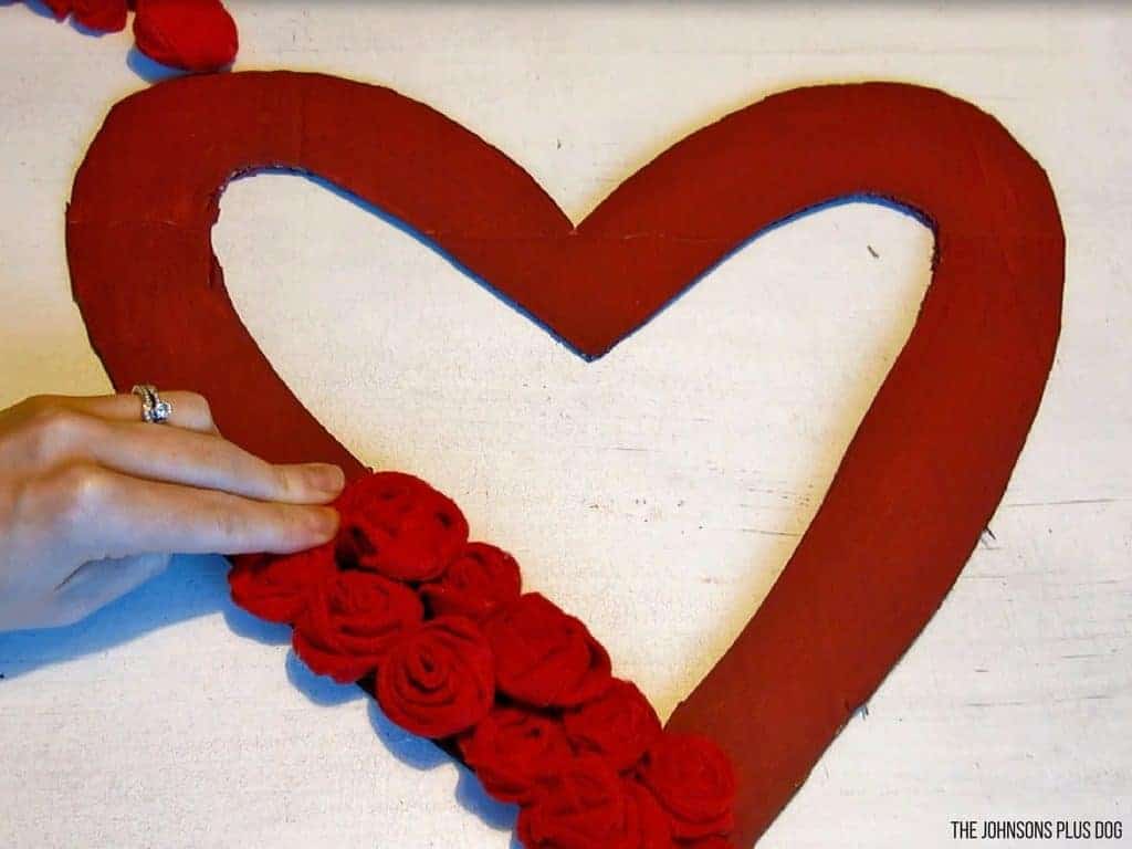 Woman attaching the DIY rosettes felt in the DIY red heart shaped cardboard