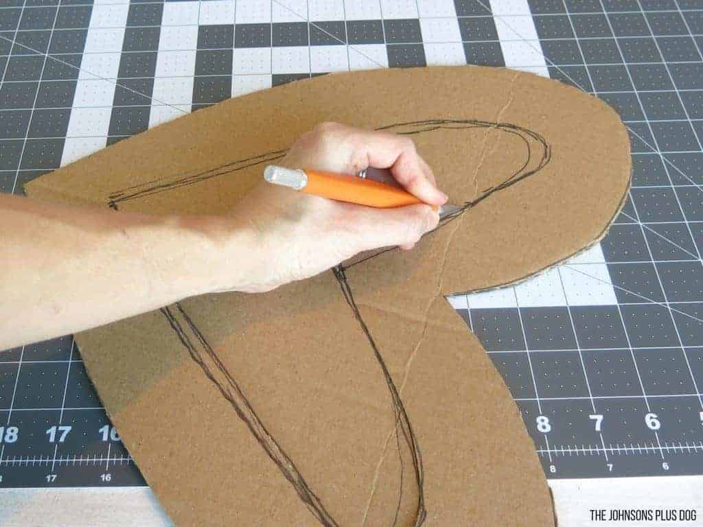 Woman hand holding a cutting cutting a heart shape from the cardboard