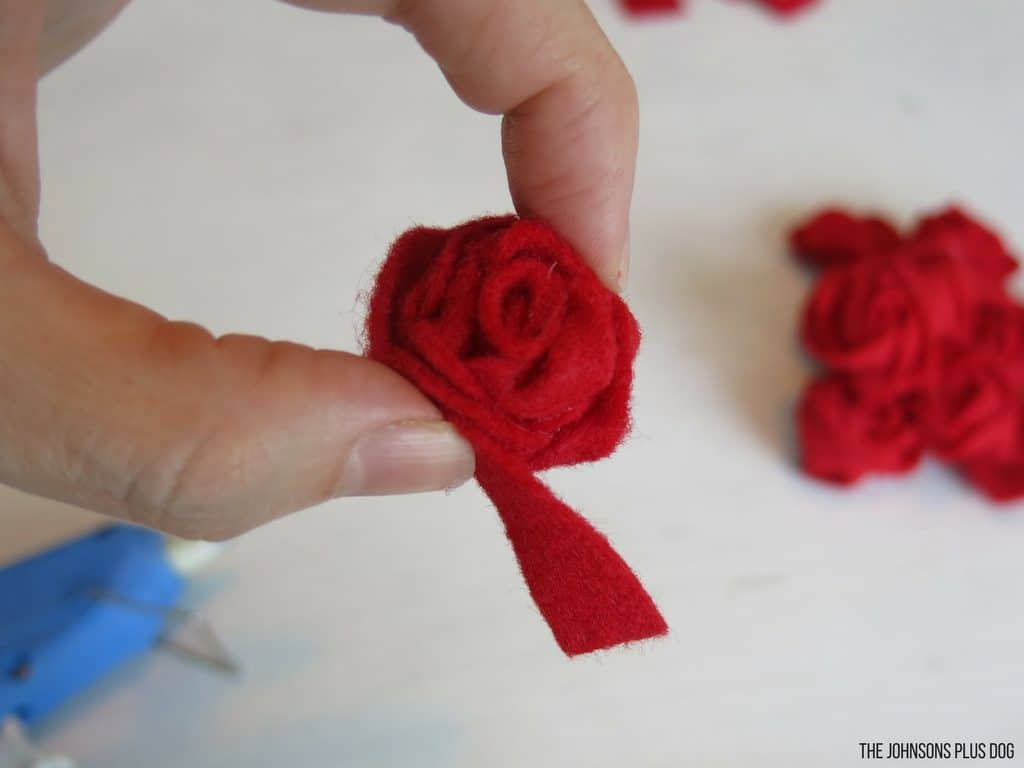 Woman hand pressing a rosette rolled red felt strip