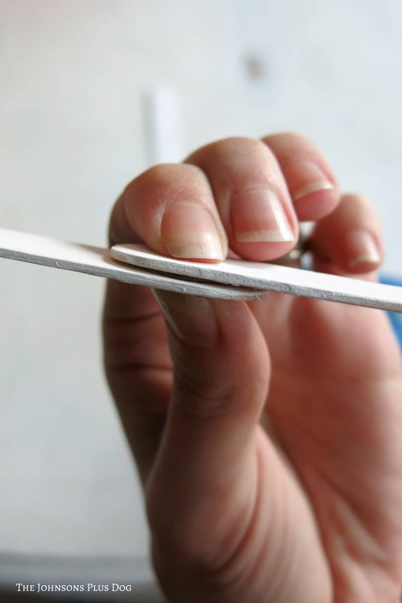 Woman hand attaching ends of popsicle sticks with glue to make snowflakes