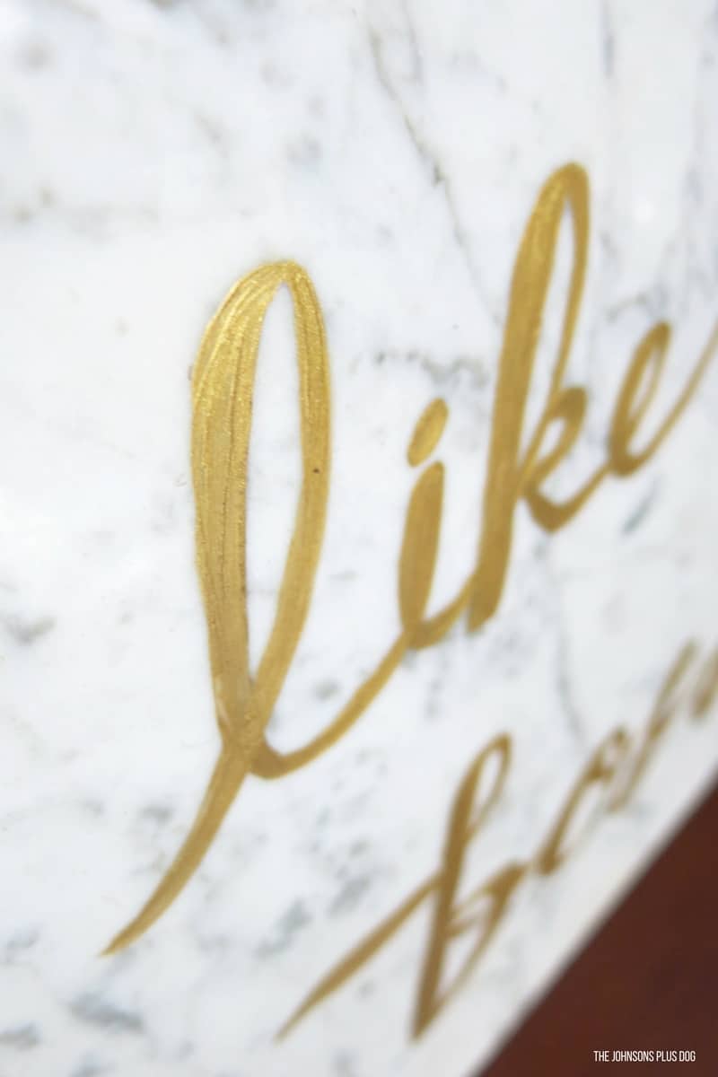 A close up side angle look at the painted gold letters on a marble slab. This glam office decor is a a fun DIY project that spruces up any office space.