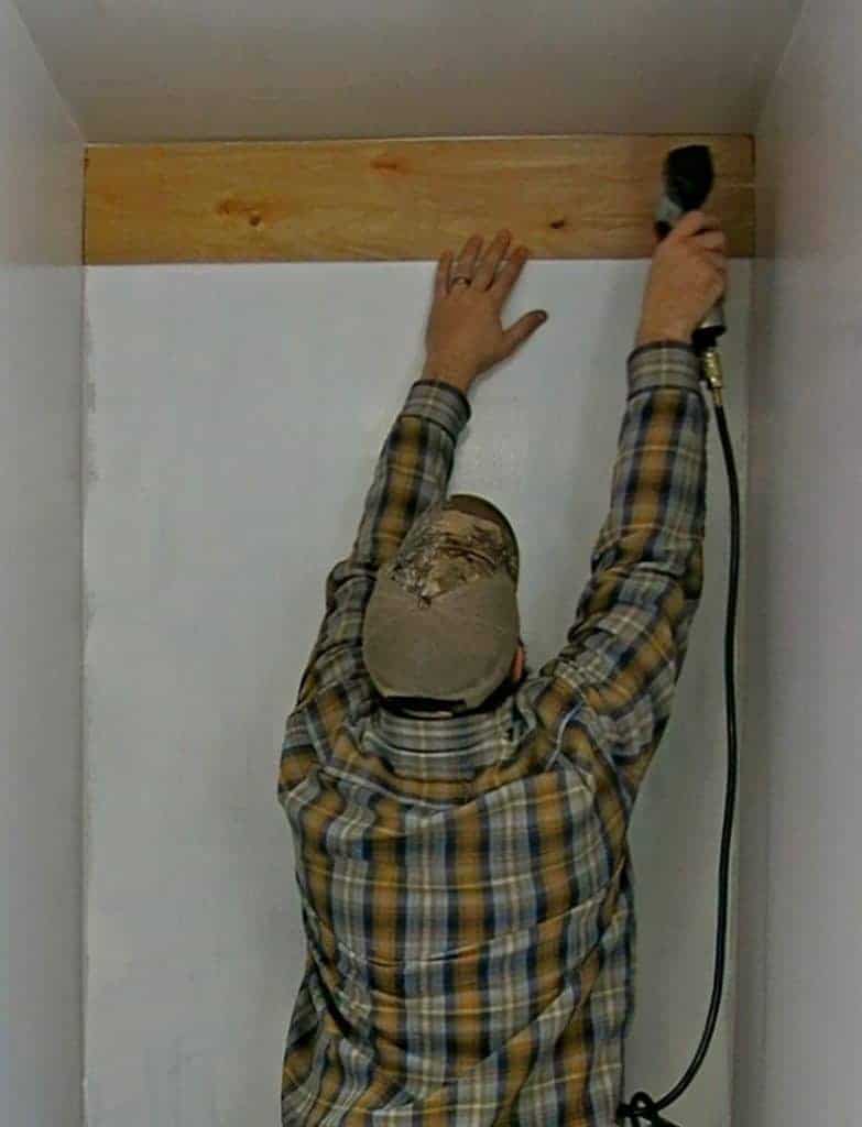 Using a nail gun, nail the unpainted shiplap planks to the wall.