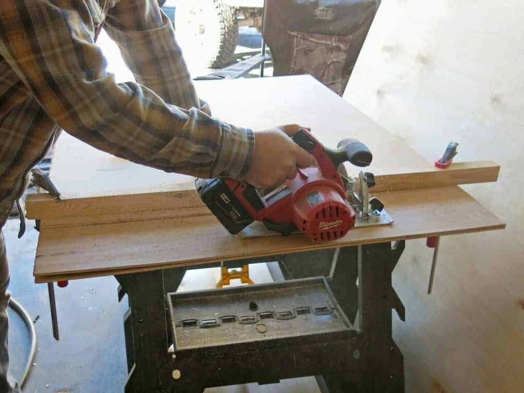Logan cuts the faux shiplap wood using a skill saw. This is how you'd cut shiplap without a table saw.