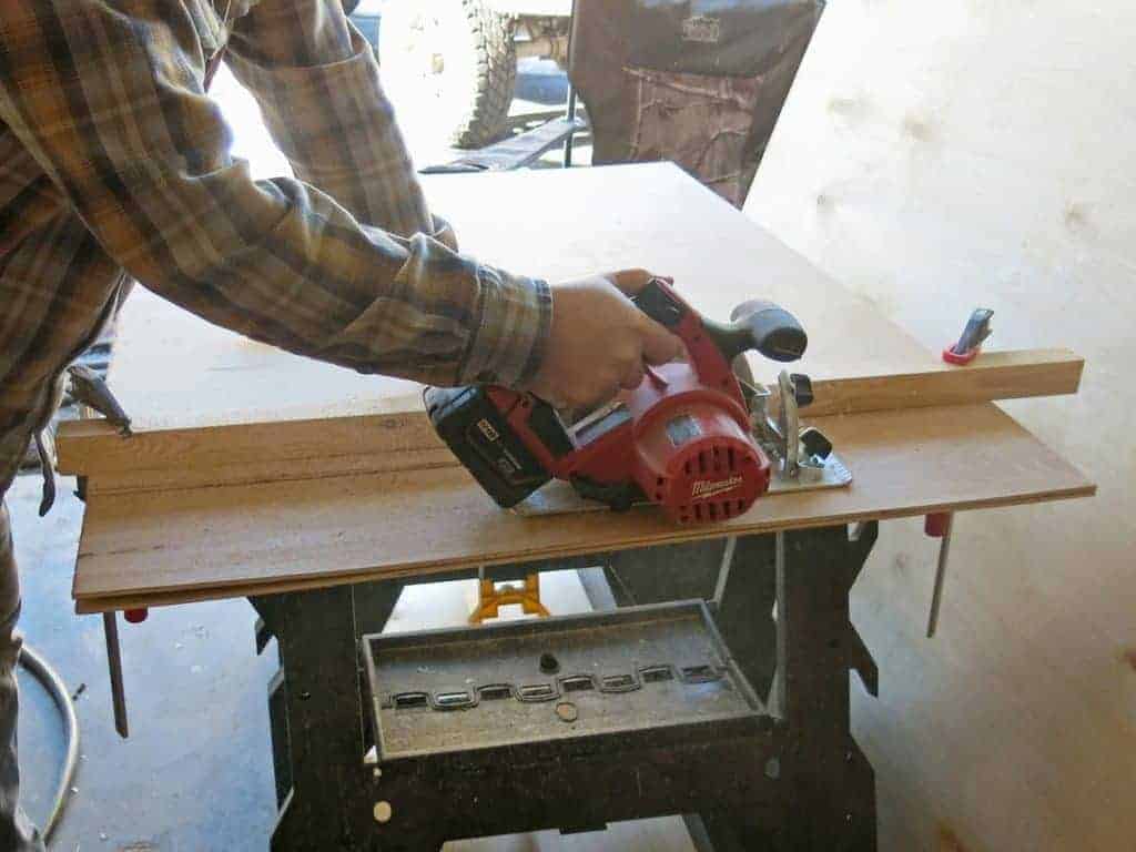 Logan cuts the faux shiplap wood using a skill saw. This is how you'd cut shiplap without a table saw.