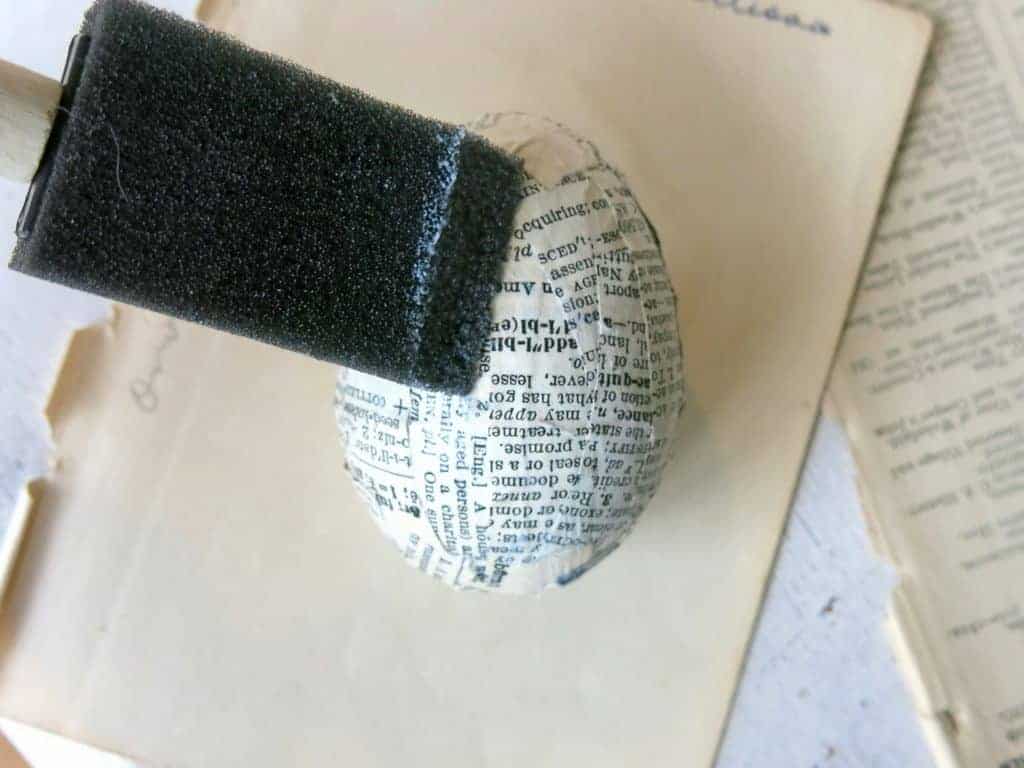 Apply a thin coat of mod podge to seal the book pages to the plastic easter egg