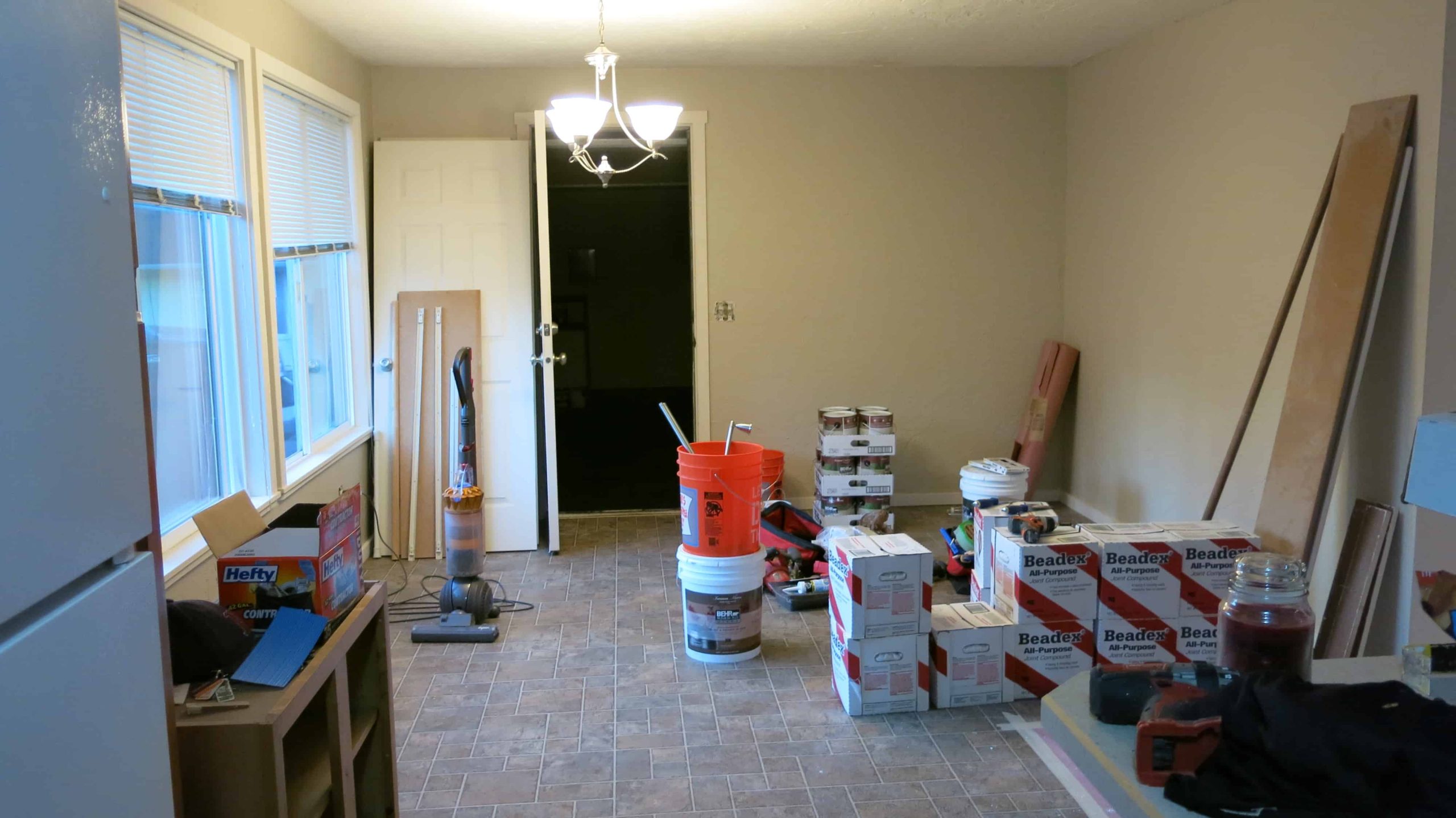 The small dining room during renovations. The room has white walls and is filled renovation supplies.