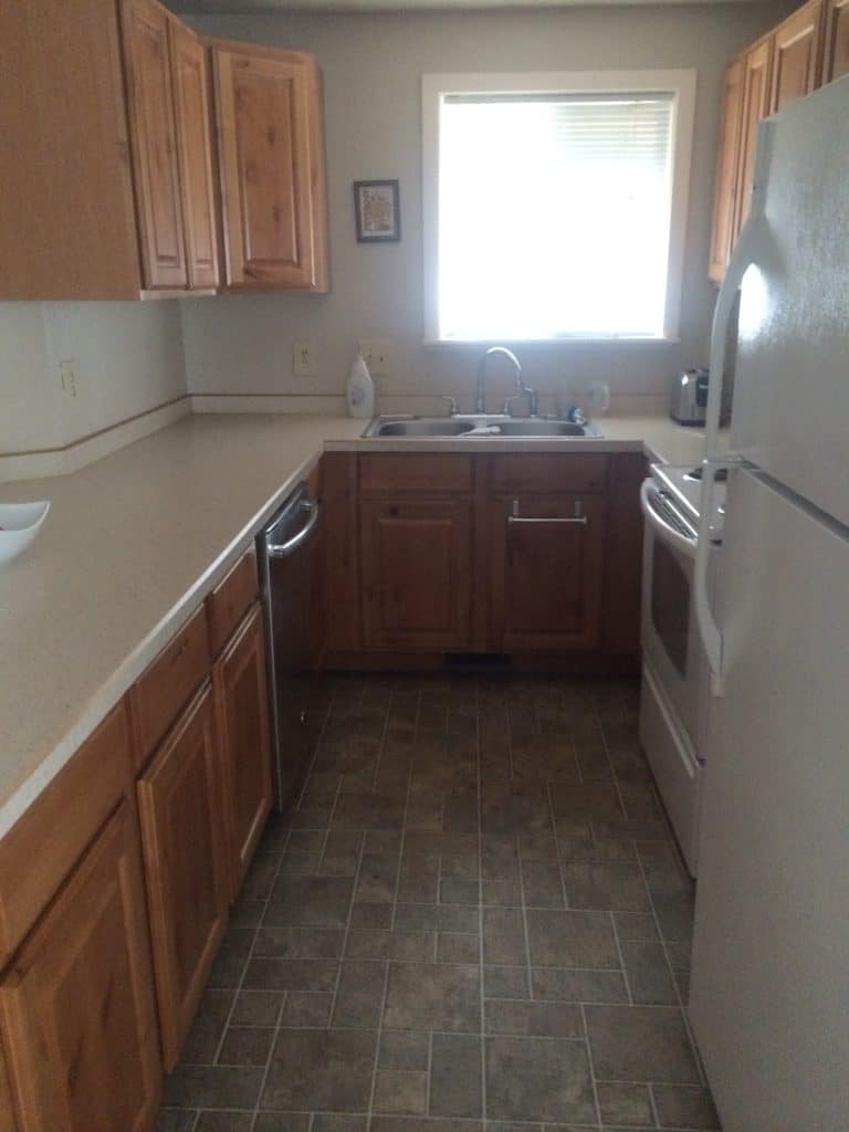 Alley style kitchen with window over sink, wood cabinets and tan laminate countertops