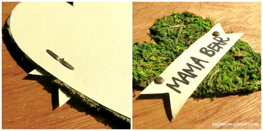 metal tags hold the name badge onto the moss heart for this adorable rustic baby shower name tag