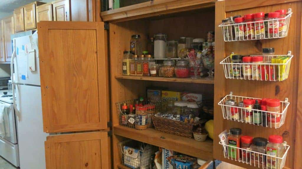 Entertainment Center converted to Pantry with wire shelving and wire baskets on the inside of the door filled with spices