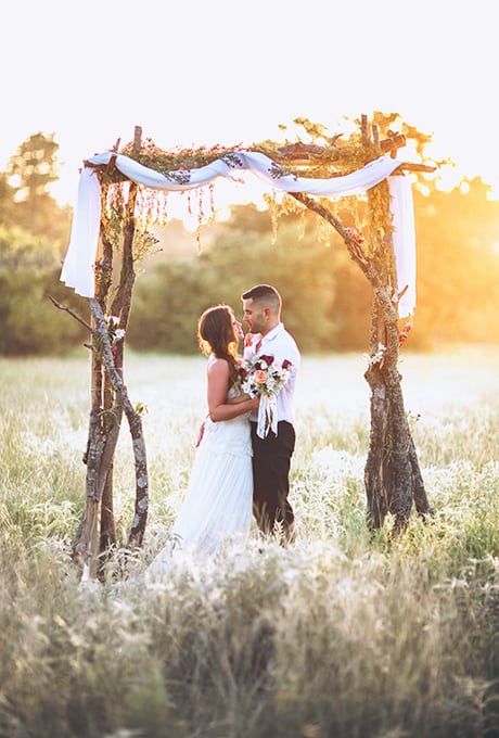 Creative Wedding Ceremony Decor Ideas | Arbor made with rustic branches in field for wedding ceremony