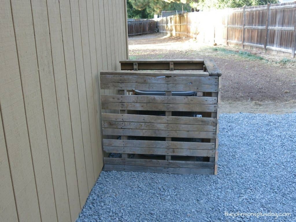 A side view of our new DIY pallet wood AC unit cover, where you can see how effectively the cover hides the AC unit from view.