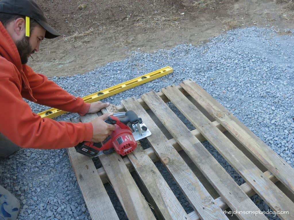 Cutting our pallet wood AC unit cover down to size using a circular saw.