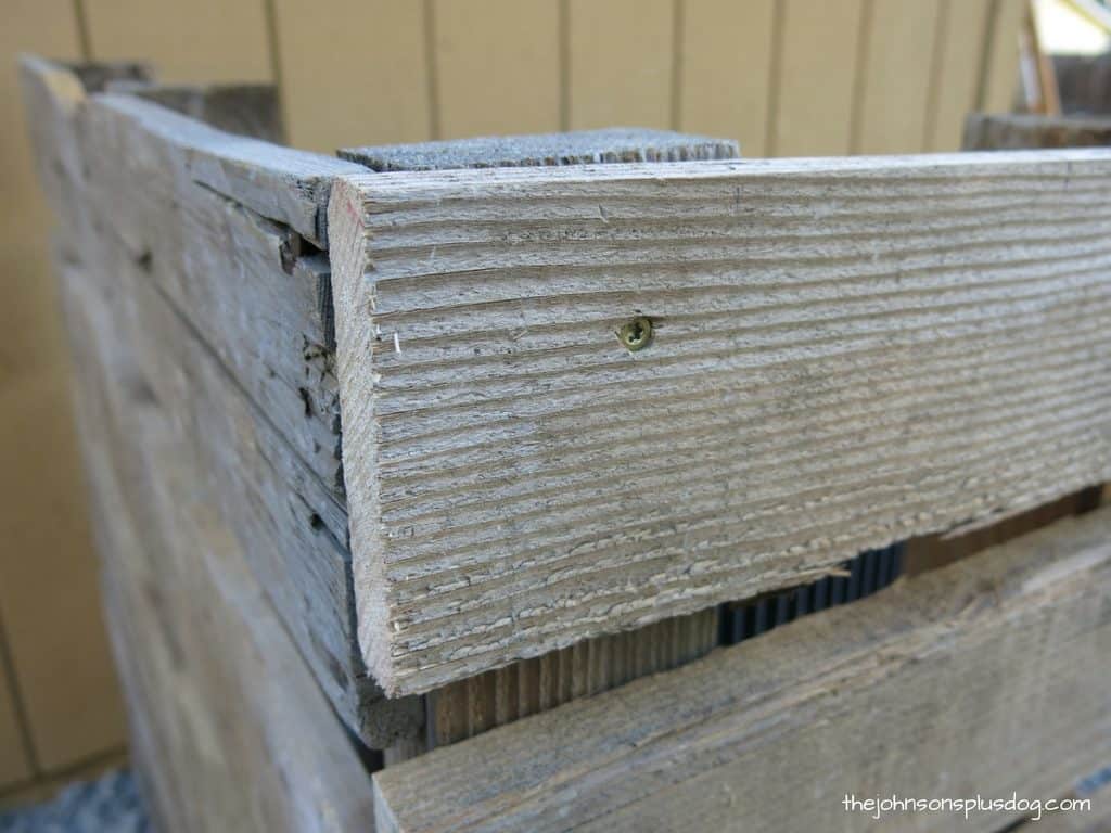A close up look at the joints of the pallet wood AC unit cover, where screws hold the wooden bars to the wood posts.