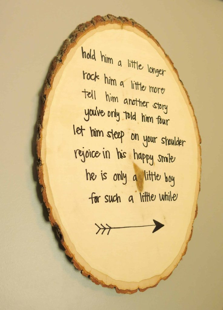 a round wooden art piece with a poem that reads "hold him a little longer, rock him a little more, tell him another story you've only told him four, let him sleep on your shoulder, rejoice in his happy smile, he is only a little boy for such a little while"