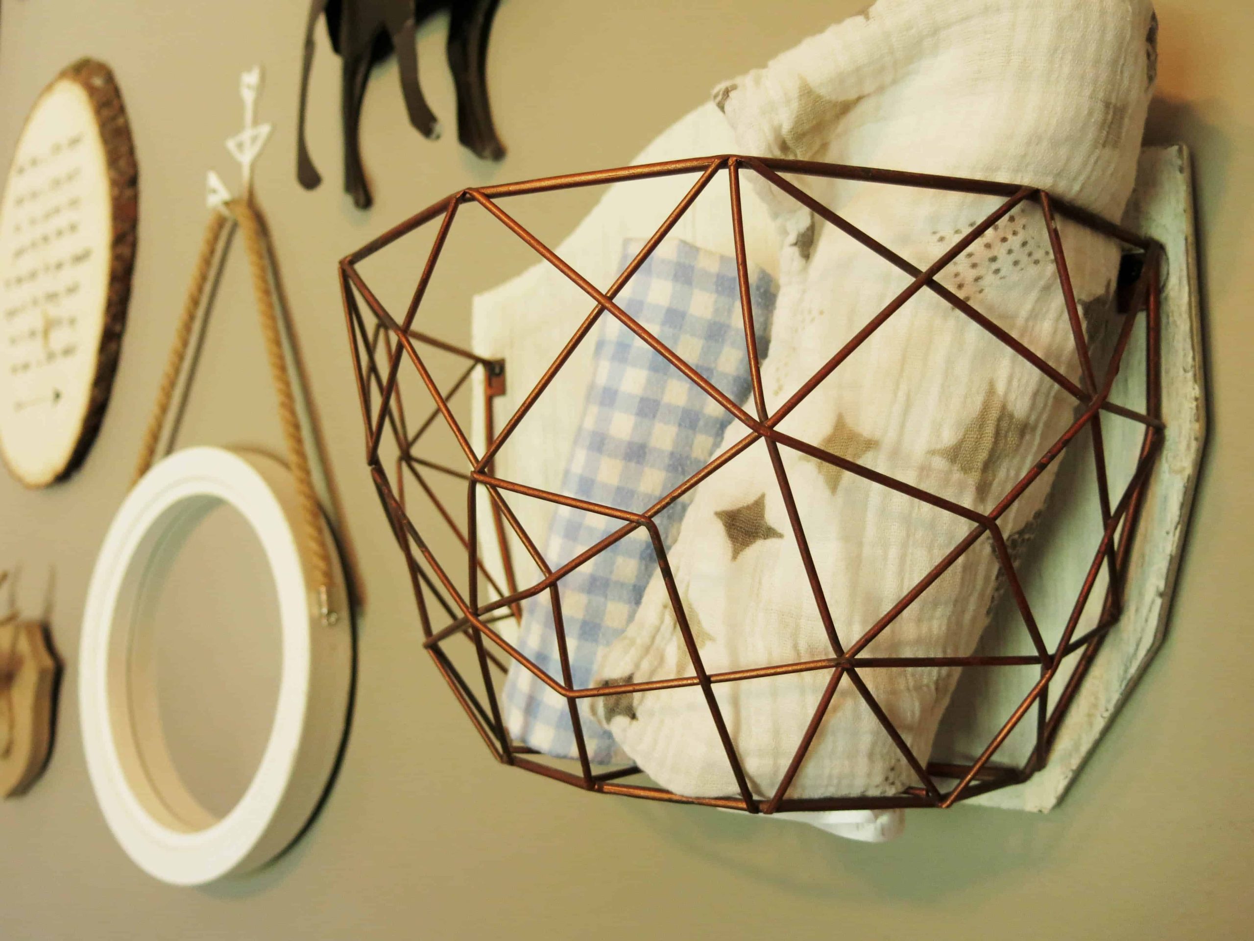 a wire basket attached to a wall, with blankets in it