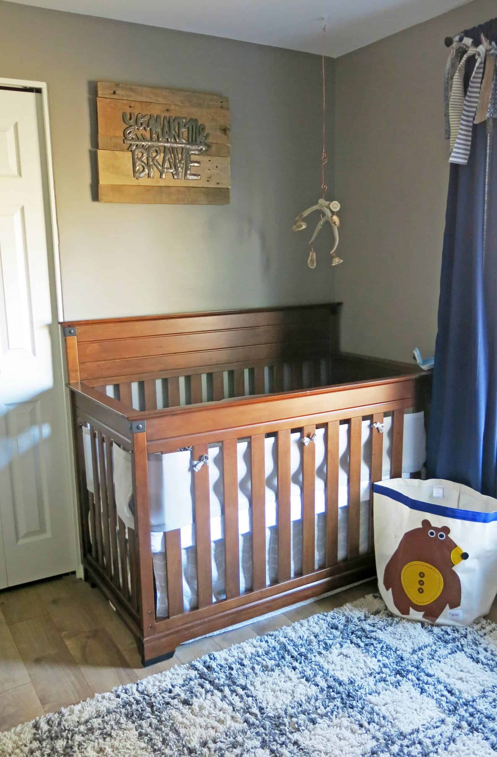 The baby's crib -- a dark wooden crib with blue sheets -- in the corner of his nursery.