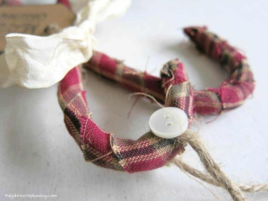 Attaching a single button the to jute-string hanger on the hook of the homemade fabric candy cane ornaments.
